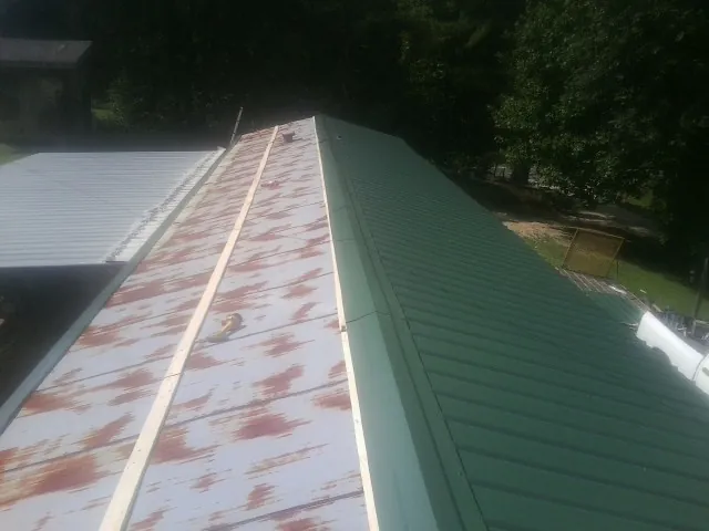 Old rusted panels beside newly installed green metal roofing — Wind Damage Roof Repair by Roofing Brothers in Mercersburg