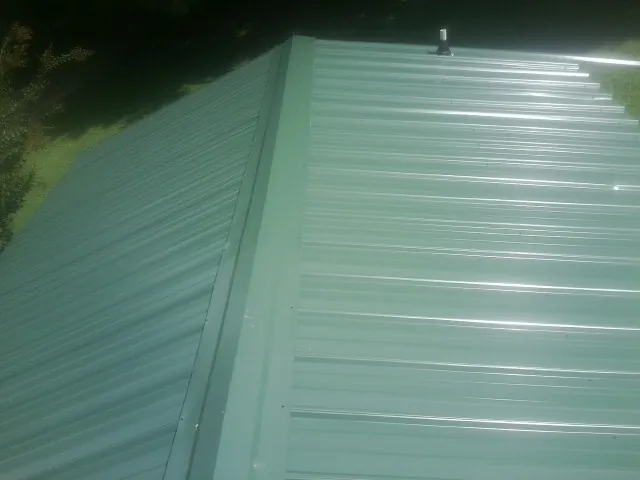 New green metal panels meeting at the ridge of a roof — Flat Roof Repair work by our crew in Mercersburg