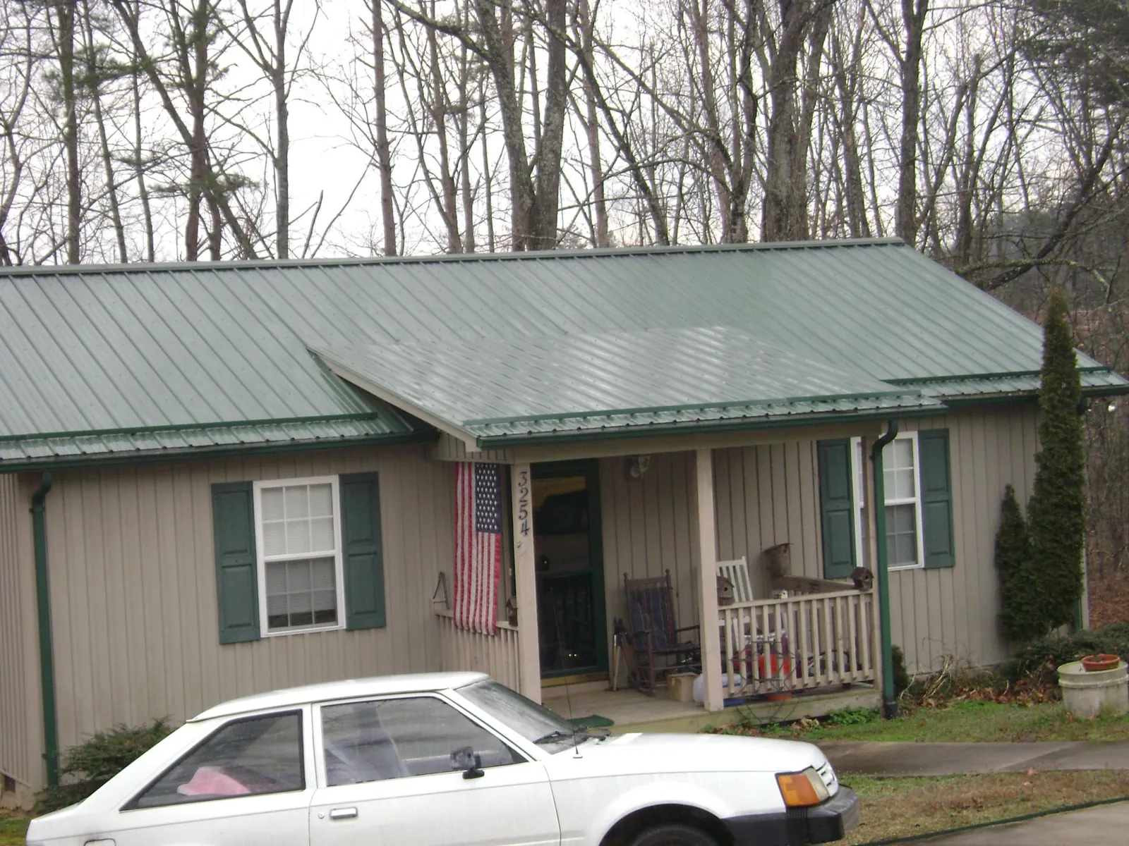 Green metal roof and front porch on a tan sided cottage in Mercersburg