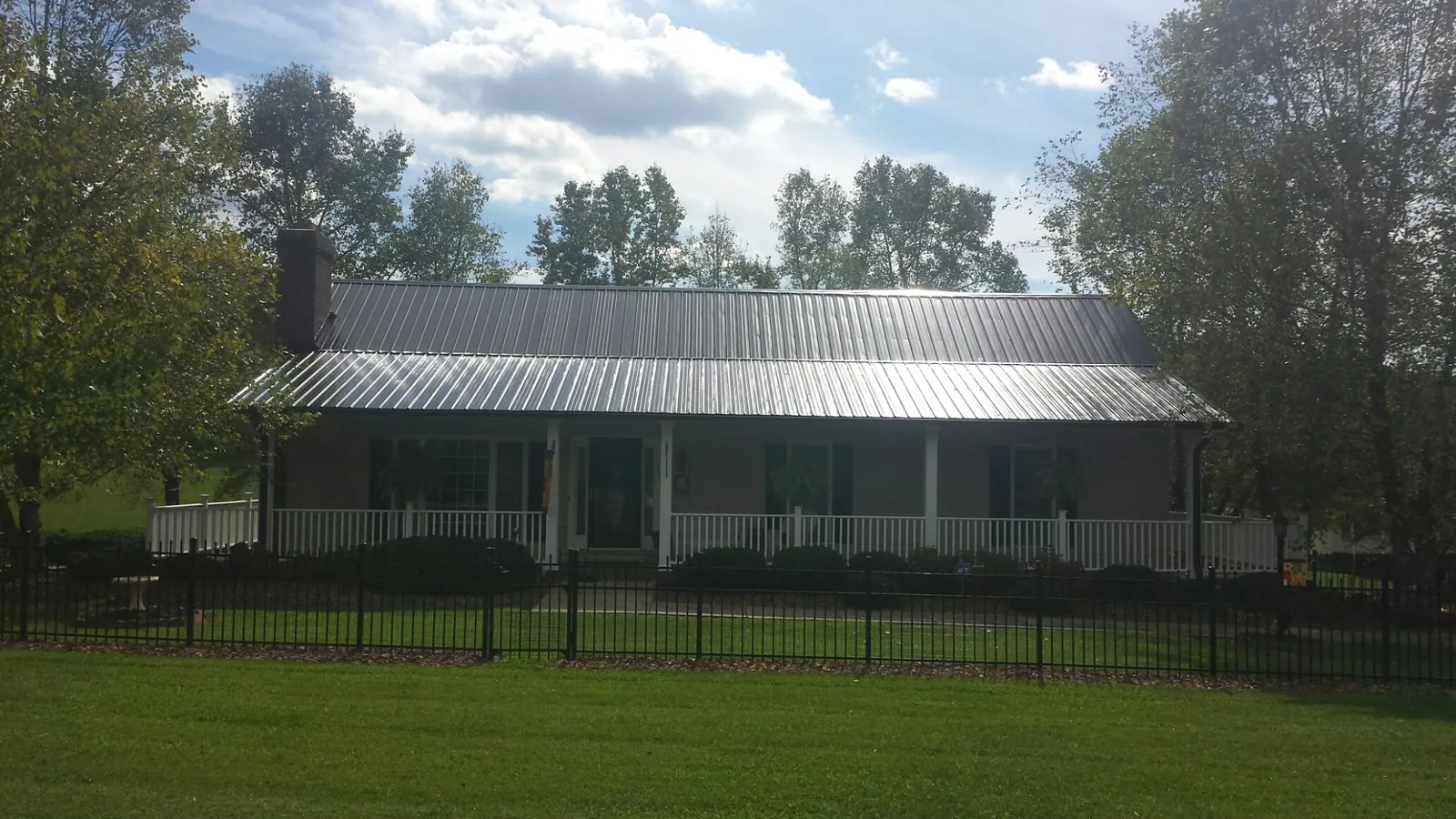 Gray metal roof on a brick ranch with a full width front porch — Gutter Guard Installation work by our crew in Mercersburg