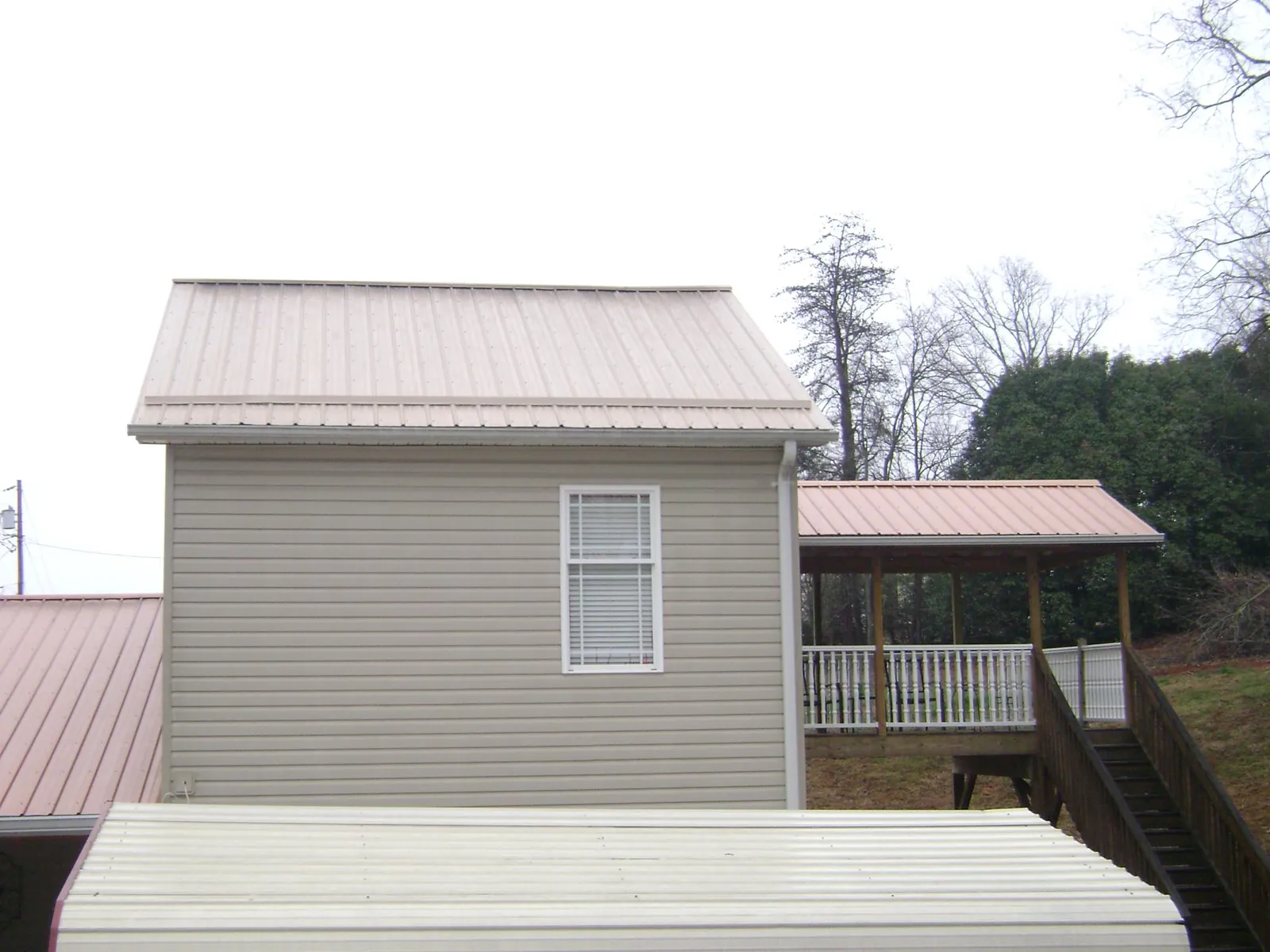 Tan metal roofs on a two story addition and attached porch, from a Roof Replacement job in Mercersburg