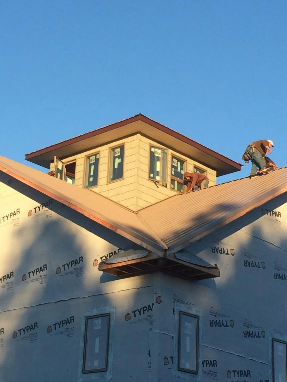Roofers working around a rooftop cupola on a new metal roof at sunset — Roof Waterproofing in Mercersburg by Roofing Brothers